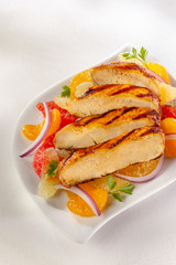 Sliced grilled chicken breast with citrus fruits. Delightful combination of chicken and acidic fruits