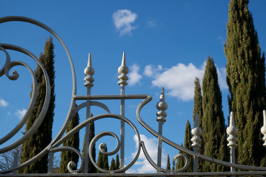 cancello in ferro con cipressi e cielo