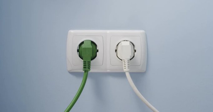Hand Plugging In a Green Power Cord into a Wall Socket as a Concept of Eco Green Energy Efficiency