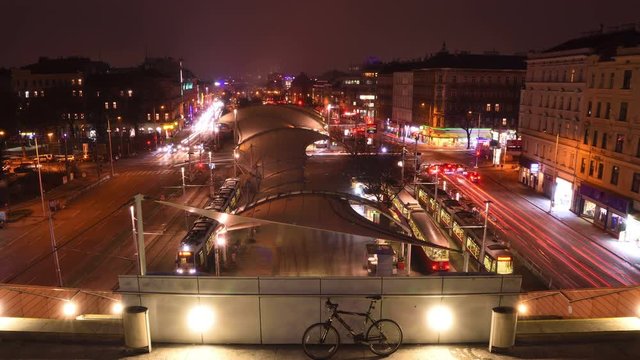 Nightly traffic time-lapse with car light trails on Guertel street seen from stairs of Vienna library above the outdoor roofing of the square.