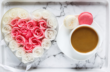 Pink and white roses in heart shaped box and coffee cup on marble table background. Delicious sweets and coffee break. Gift, present for Valentines, Mothers Day, Womans day concept. Flat lay, close up