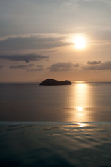 Fototapeta premium Sea island on the skyline behind infinity pool under beautiful sunset sky in Ko Pha-ngan, Thailand