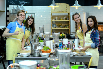 Group of three women and one man cooking and talking in the kitchen. Culinary, food and people, cooking class concept/Cooking class. young happy friends in the kitchen