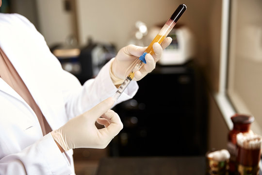 female doctor using a syringe to draw prp from a vial