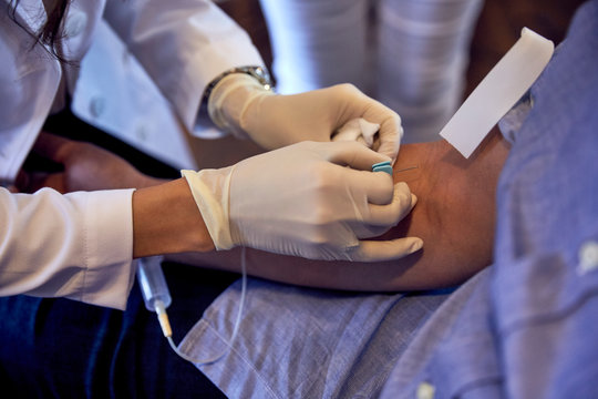 Female phlebotomist drawing blood from man