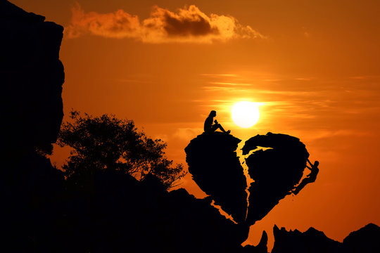 Couple on the broken heart shape rock on the mountain with red sky sunset