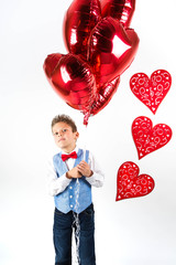 Pretty little girl boy  celebrating Saint Valentine's Day and holding red shiny balloons in shape of heart on the white background