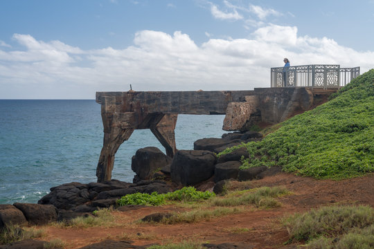 Tourist stands on the old concrete pineapple dump pier by bicycle path in Kapa'a