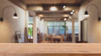 Empty wood table top and blurred bokeh cafe and coffee shop interior background with vintage filter...