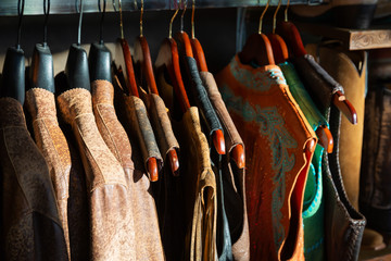Leather jacket on hangers on a rack in retail store, aligned. Lit with sunlight 