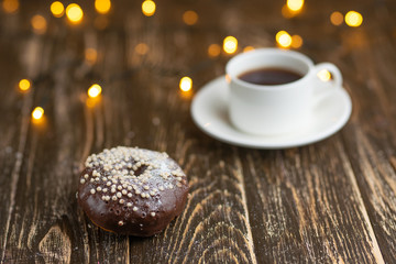 Chocolate donuts with coffee on a wooden table with beautiful lights