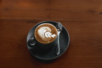 Coffee latte art on the wooden desk in coffee shop vintage color tone. Cup of coffee with beautiful Latte art