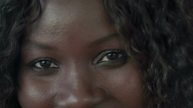 Beautiful female eyes looking at camera. Close-up partial view of happy pretty African American woman looking at camera. Emotion concept