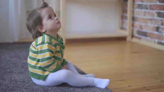 A little girl, sitting at floor and carefully watching television