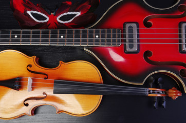 Obraz premium Electric guitar, violin and carnival mask on the dark