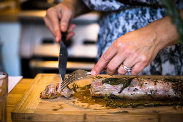 Cutting roasted pork wrapped in herbs