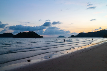 Sea wave moving to the beach with green islands and blue, yellow sky in background at the evening in Koh Mak Island at Trat, Thailand.