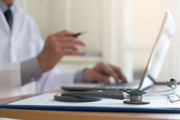 Doctor working on laptop computer and reading book