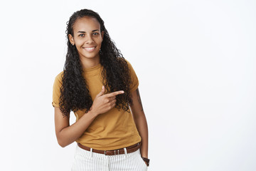 Studio shot of shy and cute pretty young african american woman with long curly hair bending as...