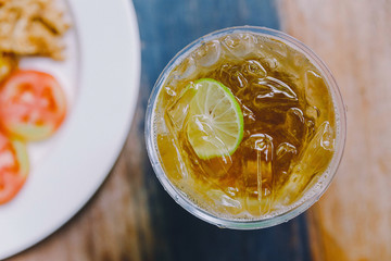 Top view of Iced Lemon Tea in plastic glass on wooden top table.