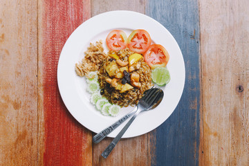 Thai Pineapple Fried Rice topping with raisin, cashews and dried shredded pork. Served with cucumber and tomato.