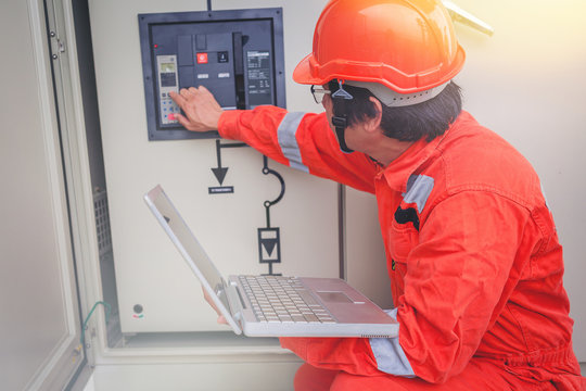 Electrical and instrument technician use laptop for guide to maintenance electric system at electric solar plant