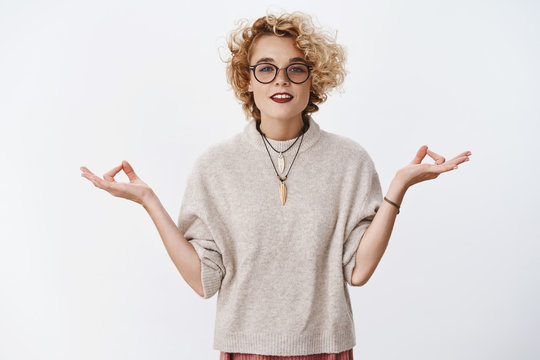 Girl Found Peace And Patience. Relaxed And Chill Woman Reaching Nirvana Looking Peaceful And Pleased At Camera Holding Hands Sideways In Lotus Pose With Zen Gesture, Meditating Over White Wall