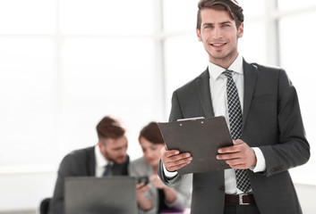 Executive businessman with clipboard standing in office