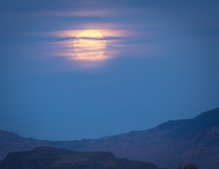 The full moon and its orange brightness is photographed in the night sky from Arizona.