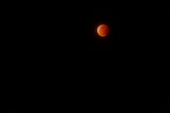 The full Lunar Eclipse in January of 2019 shows the moon in full eclipse and pictures a orangey, red moon glowing in the sky with a section on the edge with whiteish light from the glow of the sun. 