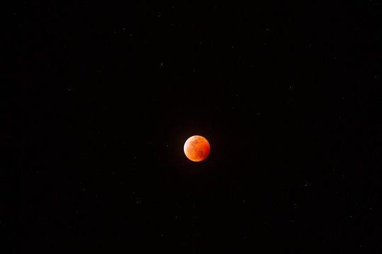 The full Lunar Eclipse in January of 2019 shows the moon in full eclipse and pictures a orangey, red moon glowing in the sky with a section on the edge with whiteish light from the glow of the sun. 