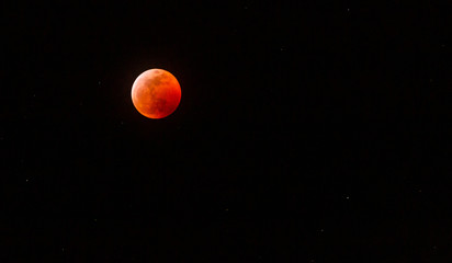 The full Lunar Eclipse in January of 2019 shows the moon in full eclipse and pictures a orangey, red moon glowing in the sky with a section on the edge with whiteish light from the glow of the sun. 