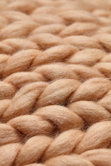 Merino wool handmade knitted large blanket, super chunky yarn, trendy concept. Close-up of knitted blanket, merino wool background. designer blanket made of beige smoky wool