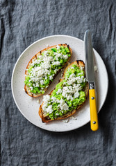 Avocado, goat cheese, grilled ciabatta sandwiches on grey background, top view. Copy space