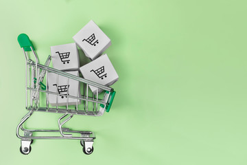 Shopping cart with boxes on green background. The concept of delivering and online shopping.