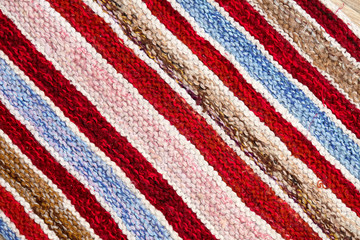 different colored stripes on the knitted fabric surface. background close-up of textiles retro rugs or rugs. the texture of the fabric is a combination with the geometry of the lines. handmade product