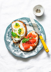 Healthy breakfast, snack, tapas - sandwiches with cream cheese, boiled egg and smoked salmon on a light background, top view