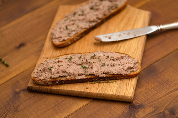 Homemade chicken liver pate on bread over on wooden background. Delicious breakfast.