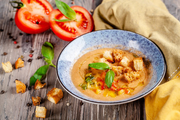Concept of Spanish cuisine. Tomato soup Gazpacho from fresh tomatoes. Beautiful serving dishes in a blue plate on a wooden table in a restaurant. background image. copy space