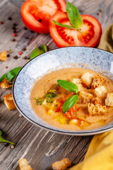 Concept of Spanish cuisine. Tomato soup Gazpacho from fresh tomatoes. Beautiful serving dishes in a blue plate on a wooden table in a restaurant. background image. copy space