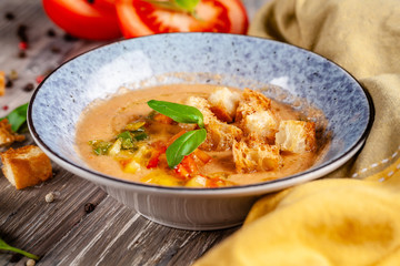 Concept of Spanish cuisine. Tomato soup Gazpacho from fresh tomatoes. Beautiful serving dishes in a blue plate on a wooden table in a restaurant. background image. copy space