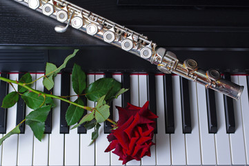 Flute and red rose on piano keyboard © yrafoto