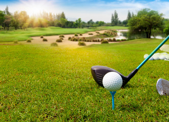 Golf ball on tee ready to be shot in green grass on blurred beautiful landscape of golf course with sunrise,sunset time on background.	