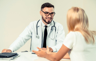 Male doctor is talking to female patient in hospital office. Healthcare and medical service.