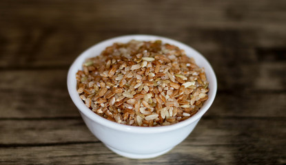 Brown rice on wood background. 