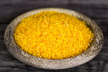 Yellow corn grits on wood background. 