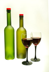 Two glasses of red wine and two bottles on white. Isolated on white