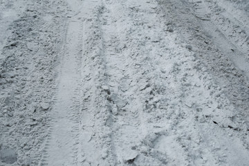 Covered with dirty snow road for movement of cars. Footprints from car in snow as abstract...