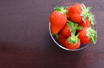 Ripe strawberries on glass over wooden background,copy space ,top view and on people
