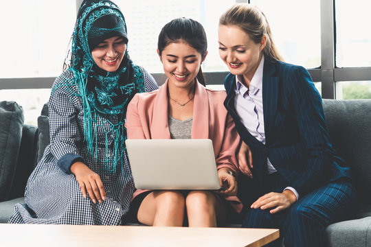 Multicultural Working Group. Team Of Businesswomen Of Different Ethnicity, Caucasian, Asian And Arabic Working Together With Laptop Computer At Office Workplace. Multiethnic Teamwork Concept.